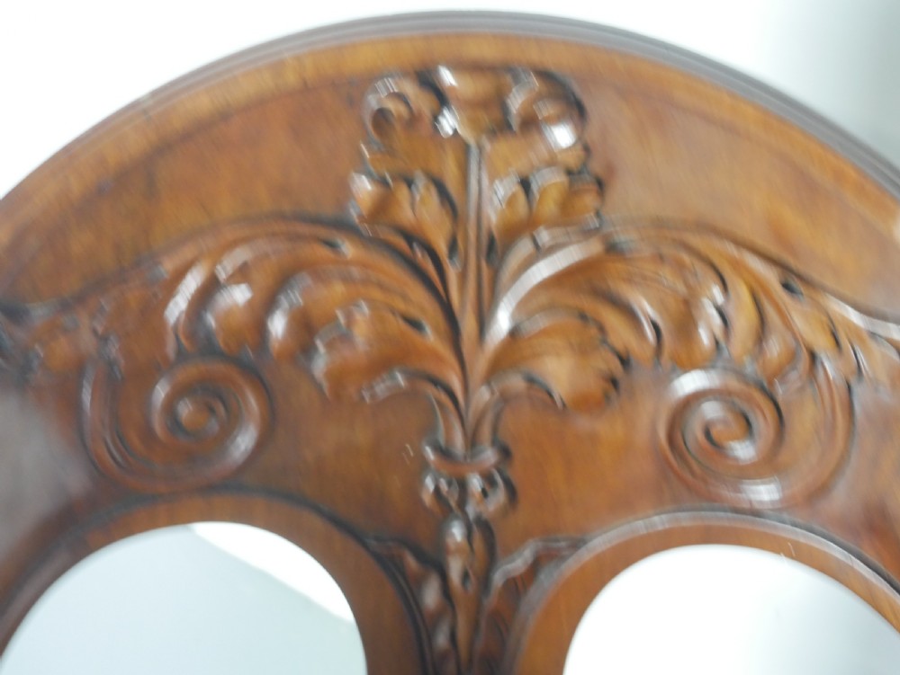 A dark mahogany Regency armchair with a carved leaf back splat, open scrolled arms, patterned upholstered seat, and turned front legs with brass castors. View II