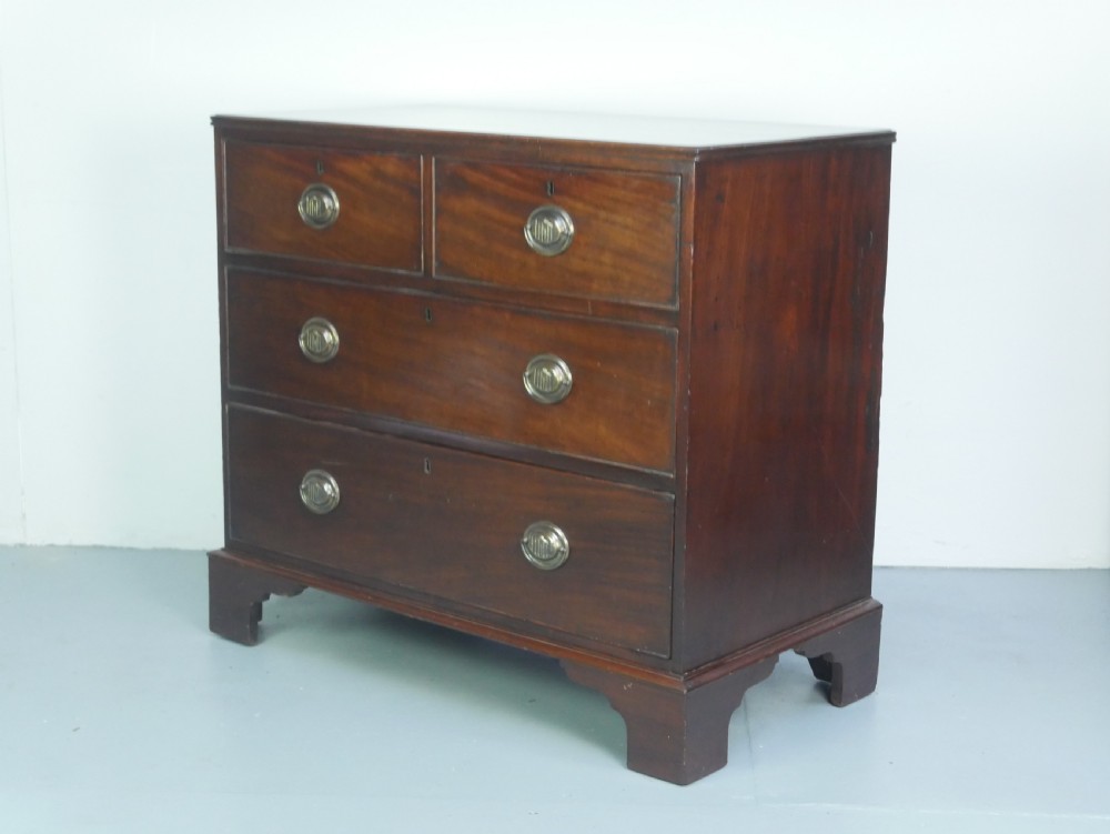 A Georgian mahogany chest of drawers featuring two short over two long graduated drawers with round brass handles and bracket feet.