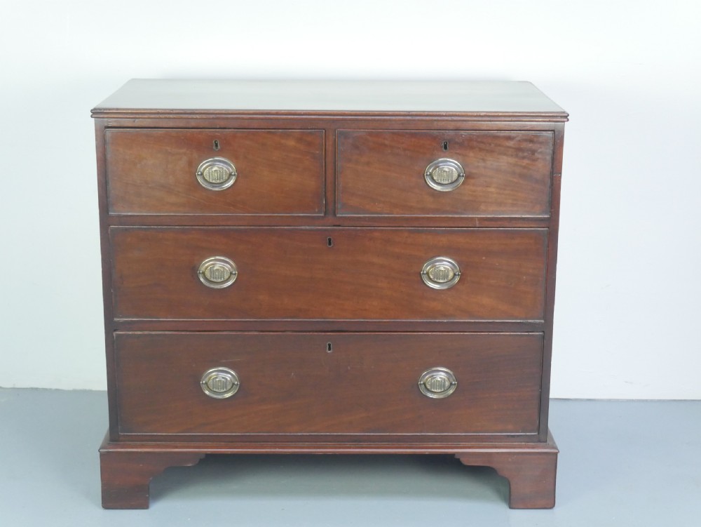 A Georgian mahogany chest of drawers featuring two short over two long graduated drawers with round brass handles and bracket feet. View II