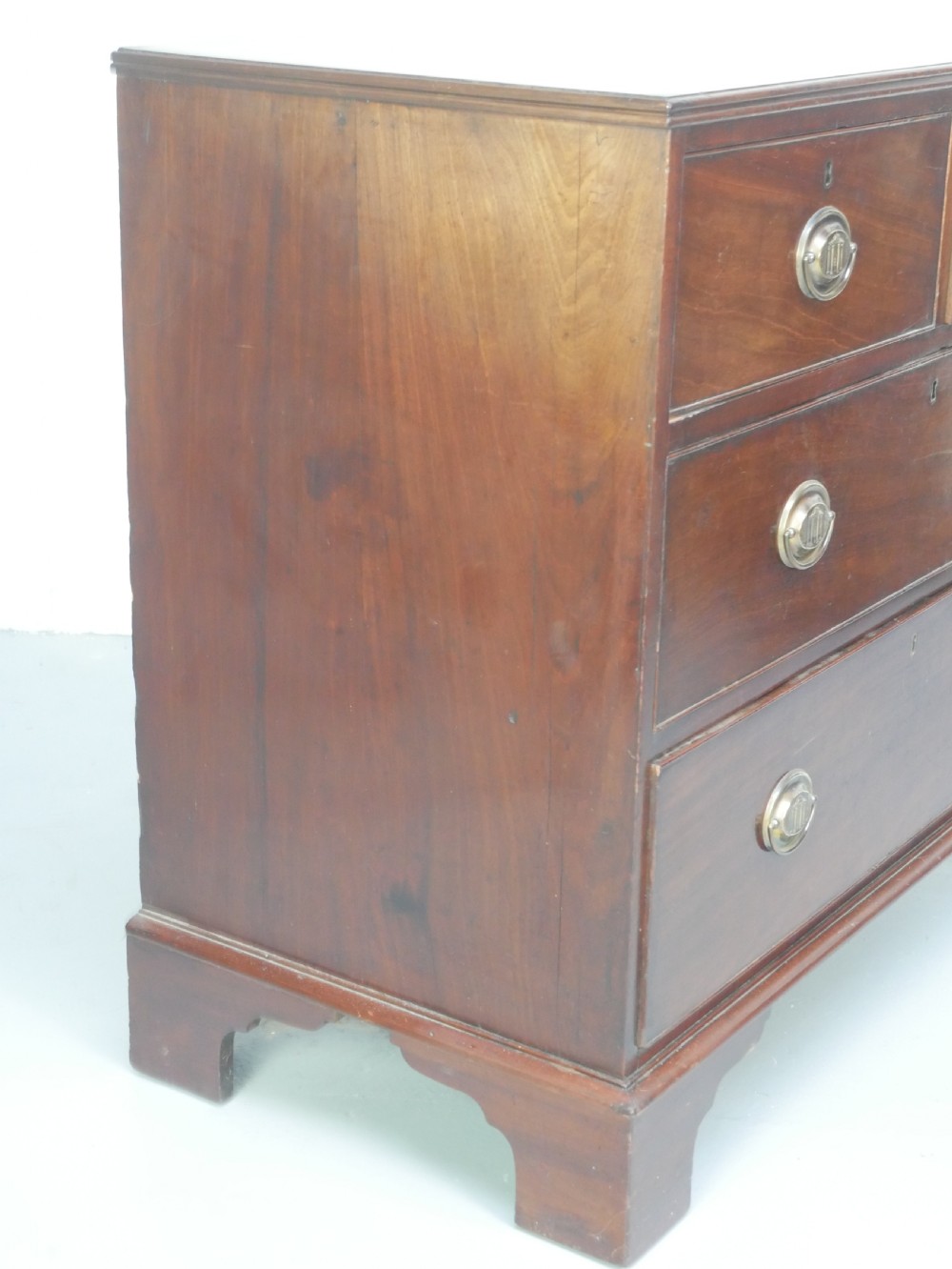 A Georgian mahogany chest of drawers featuring two short over two long graduated drawers with round brass handles and bracket feet. View III