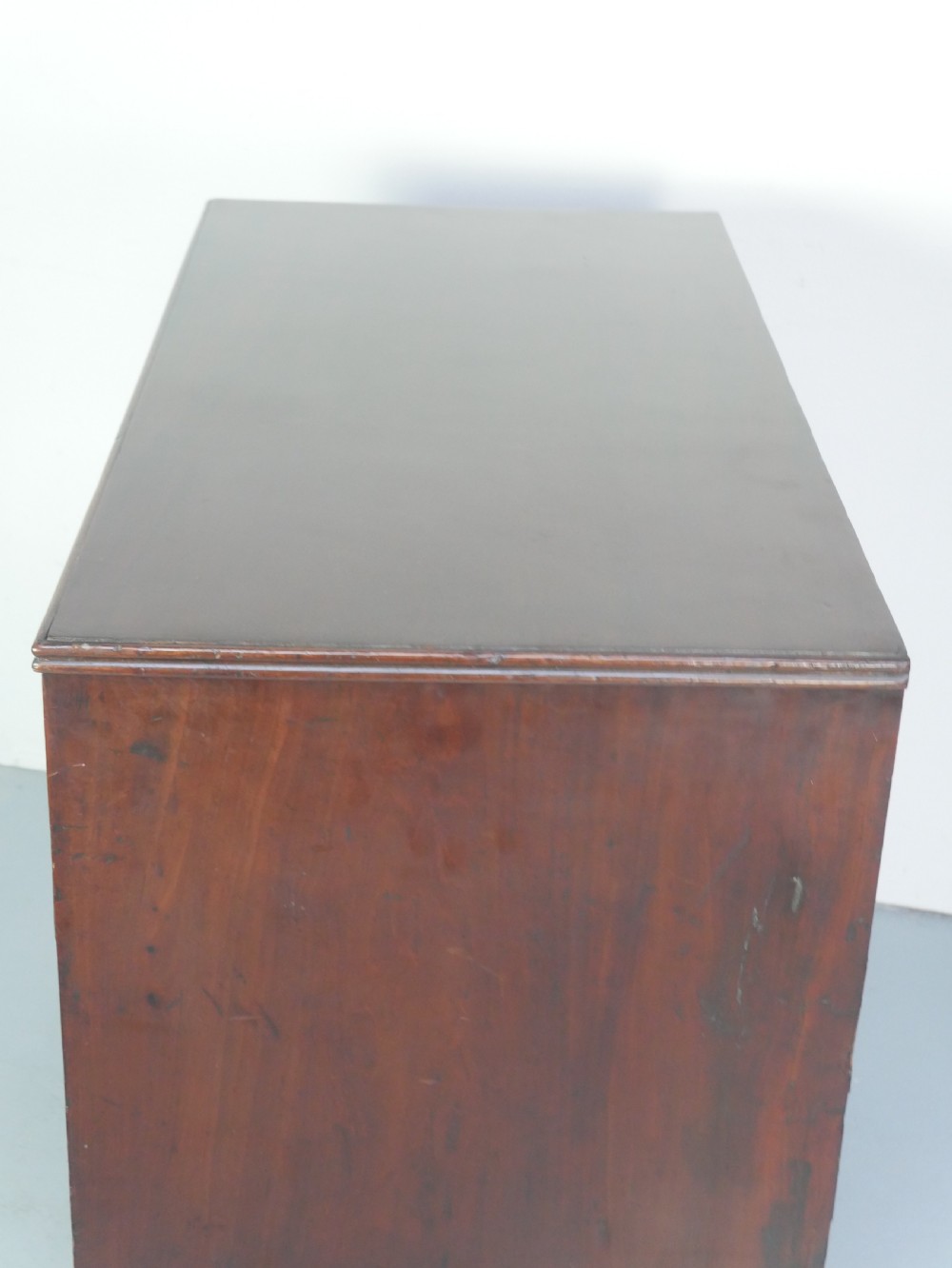 A Georgian mahogany chest of drawers featuring two short over two long graduated drawers with round brass handles and bracket feet. View V
