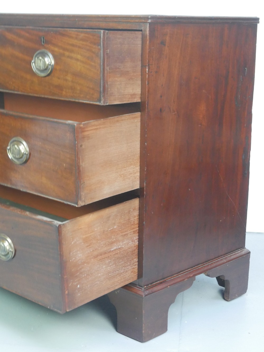 A Georgian mahogany chest of drawers featuring two short over two long graduated drawers with round brass handles and bracket feet. View VII