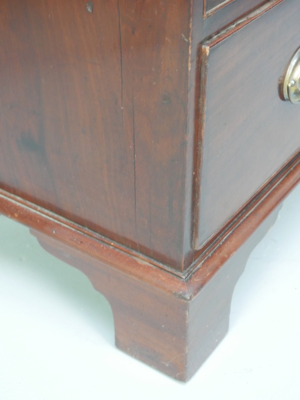 A Georgian mahogany chest of drawers featuring two short over two long graduated drawers with round brass handles and bracket feet. View IX