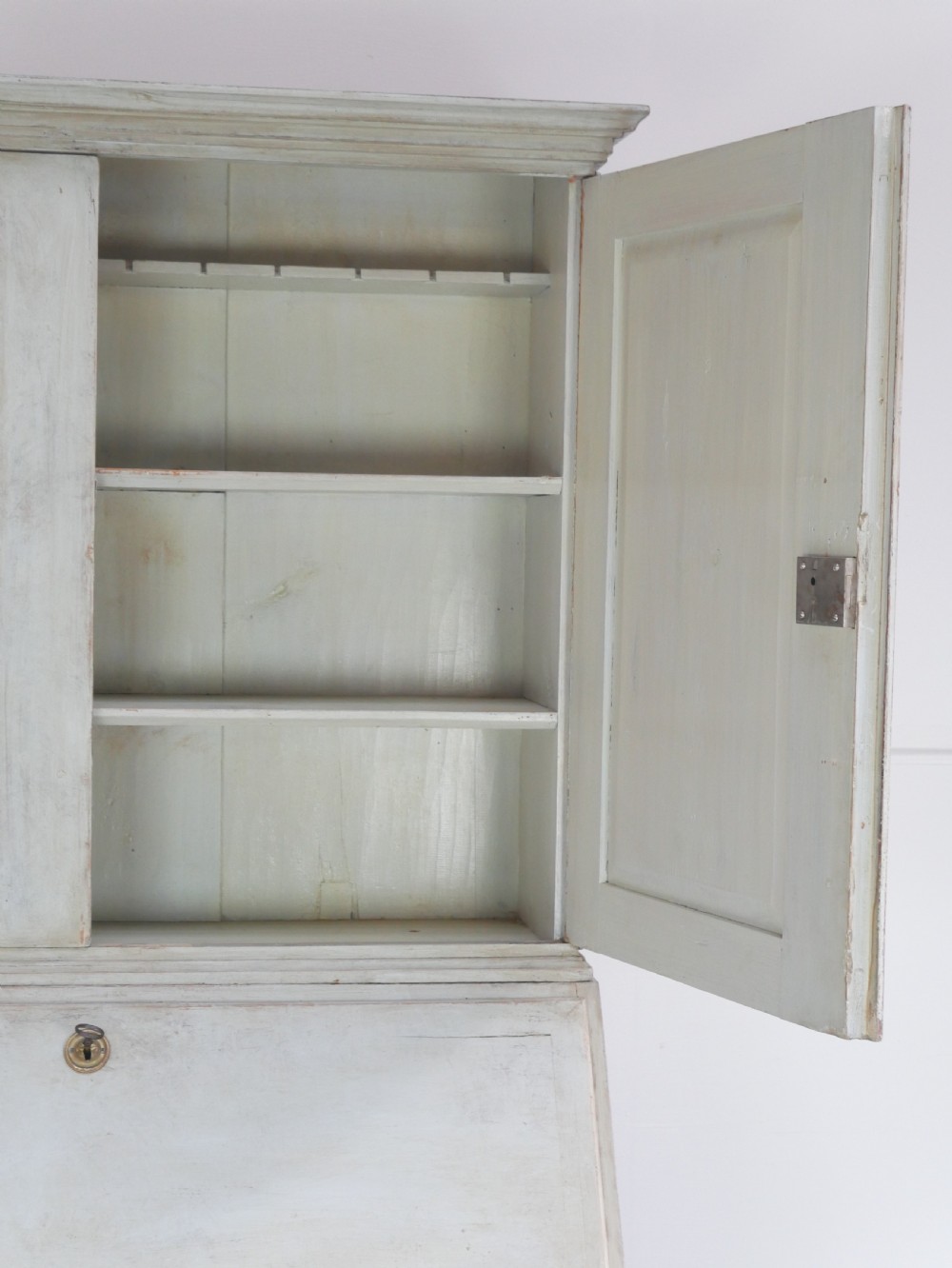A tall two-tier Swedish softwood bureau cabinet with diamond panel moulding on the doors, a slanted fall-front flap, and a distressed pale grey painted finish. View VII