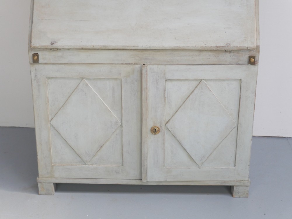A tall two-tier Swedish softwood bureau cabinet with diamond panel moulding on the doors, a slanted fall-front flap, and a distressed pale grey painted finish. View XI