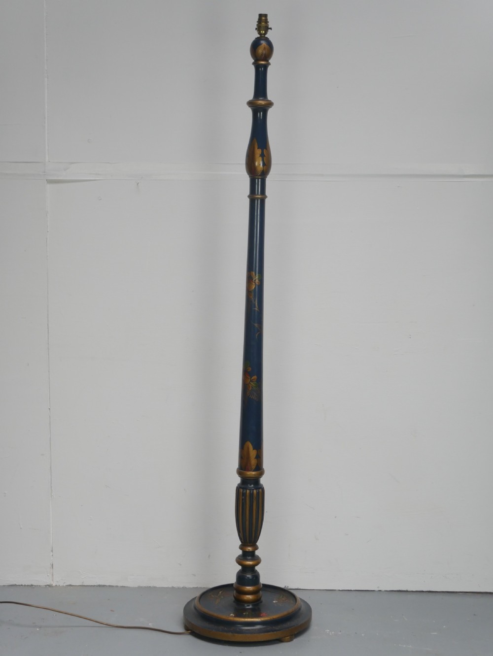 A tall turned wooden standard lamp painted dark blue with hand-painted gilt Chinoiserie botanical motifs and a circular base.