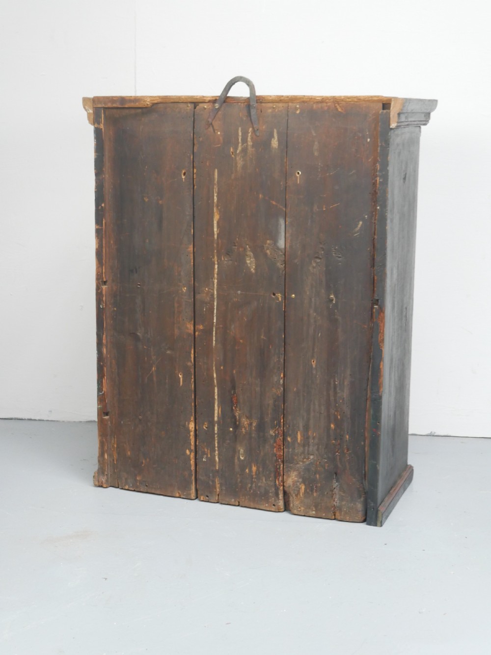 An antique dark green Swedish wall cupboard featuring hand-painted floral motifs, a central panel door, and a single lower drawer. View VI
