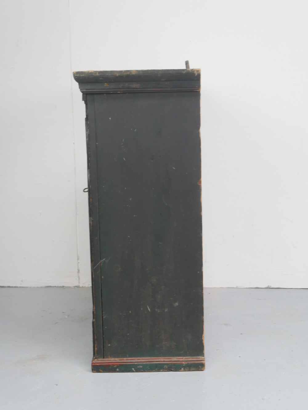 An antique dark green Swedish wall cupboard featuring hand-painted floral motifs, a central panel door, and a single lower drawer. View VII