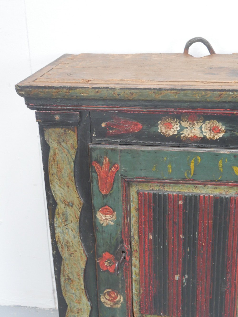 An antique dark green Swedish wall cupboard featuring hand-painted floral motifs, a central panel door, and a single lower drawer. View XII