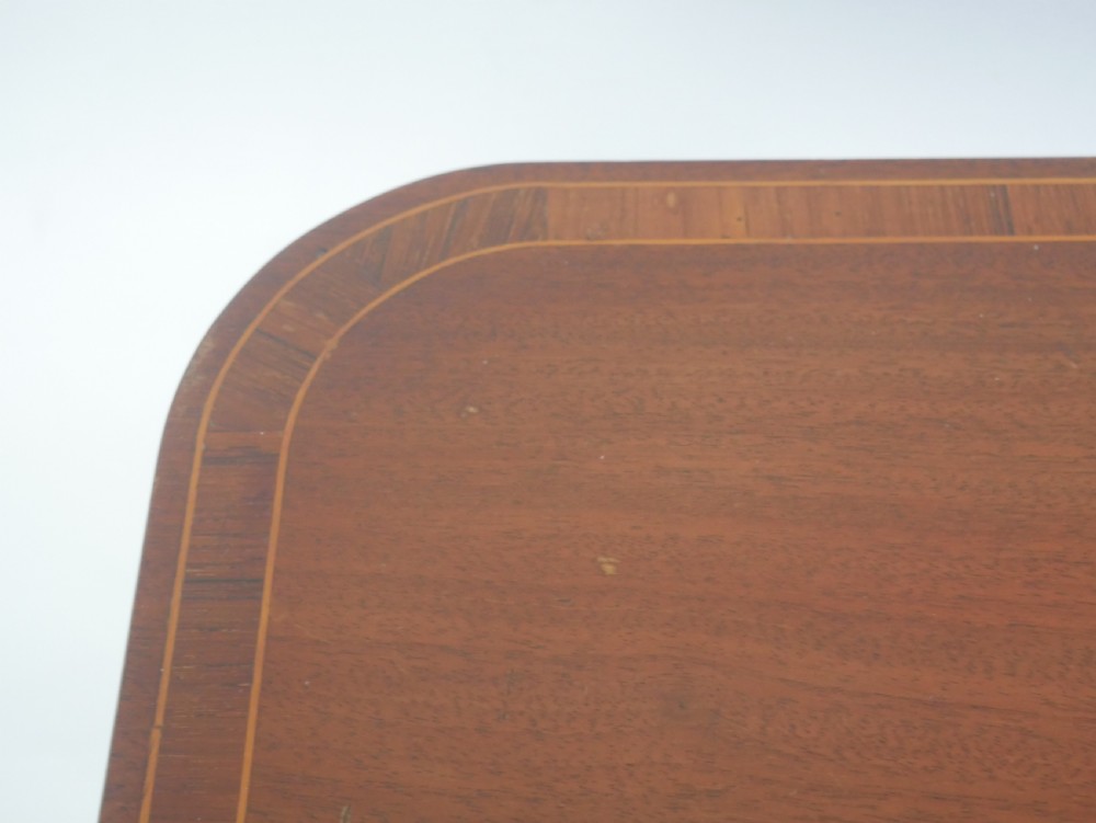 An antique mahogany tilt-top table with a rectangular inlaid tabletop raised vertically on a turned central pedestal and three curved legs. View V