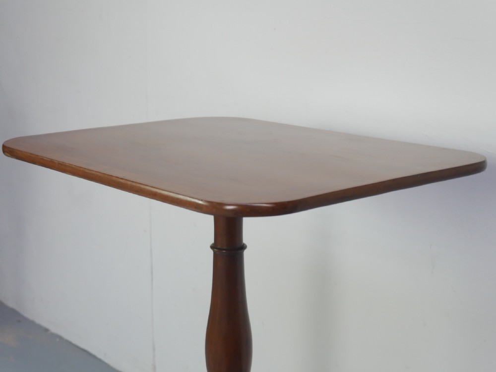 An antique mahogany tilt-top table with a rectangular inlaid tabletop raised vertically on a turned central pedestal and three curved legs. View VI