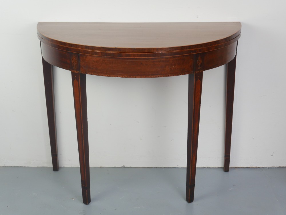A Scottish Georgian mahogany demi-lune fold-over side table with inlaid square tapered legs.