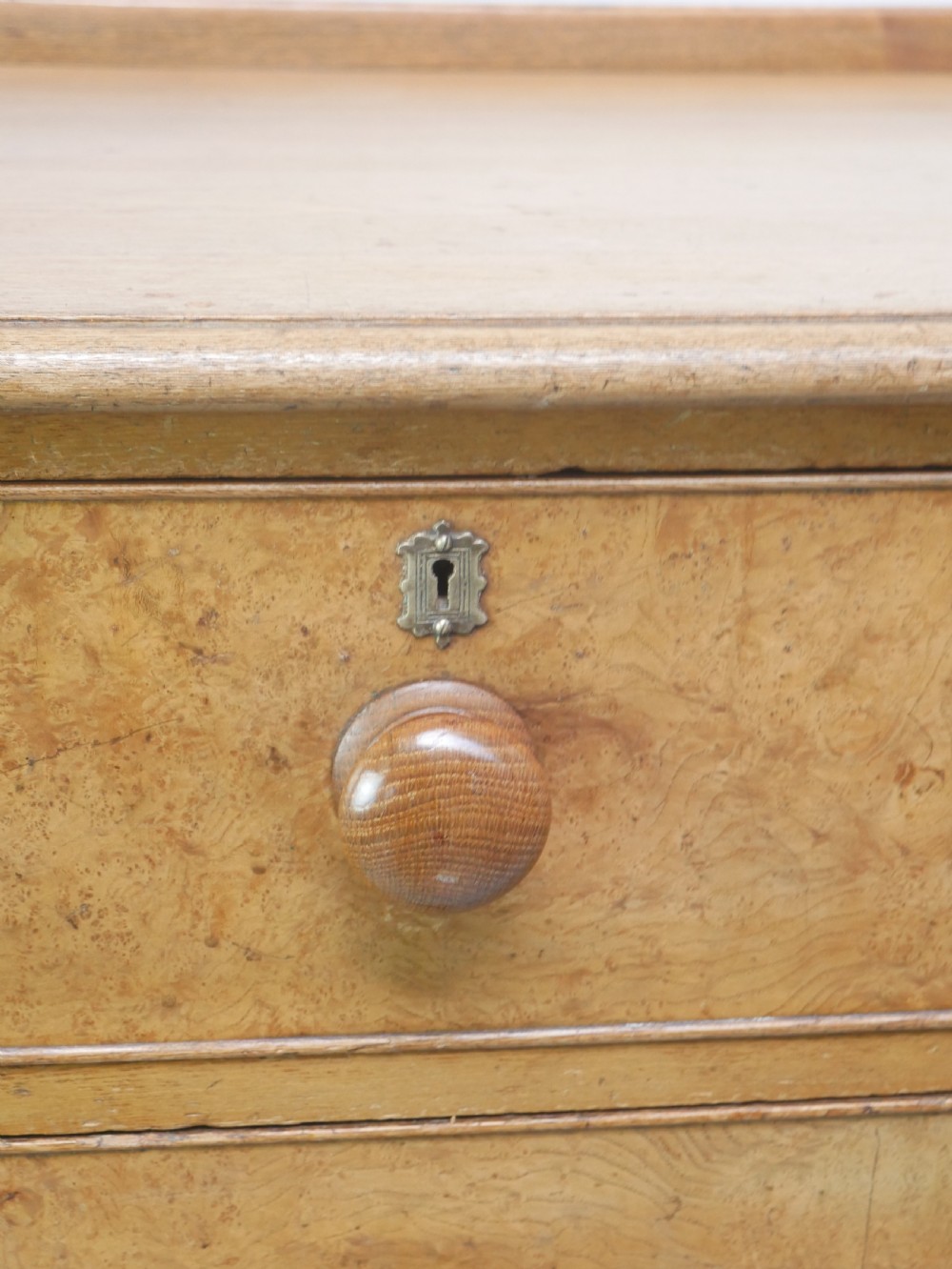 An antique burr ash chest of drawers featuring two short over three long graduated drawers with turned wooden knobs and bracket feet. View II