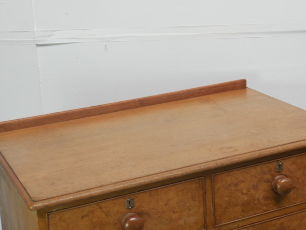 An antique burr ash chest of drawers featuring two short over three long graduated drawers with turned wooden knobs and bracket feet. View III