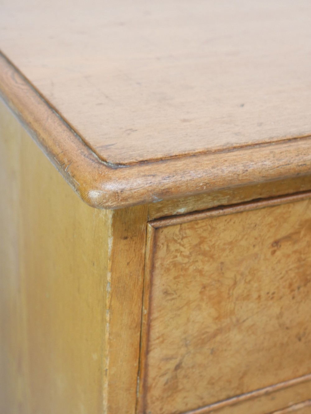 An antique burr ash chest of drawers featuring two short over three long graduated drawers with turned wooden knobs and bracket feet. View V