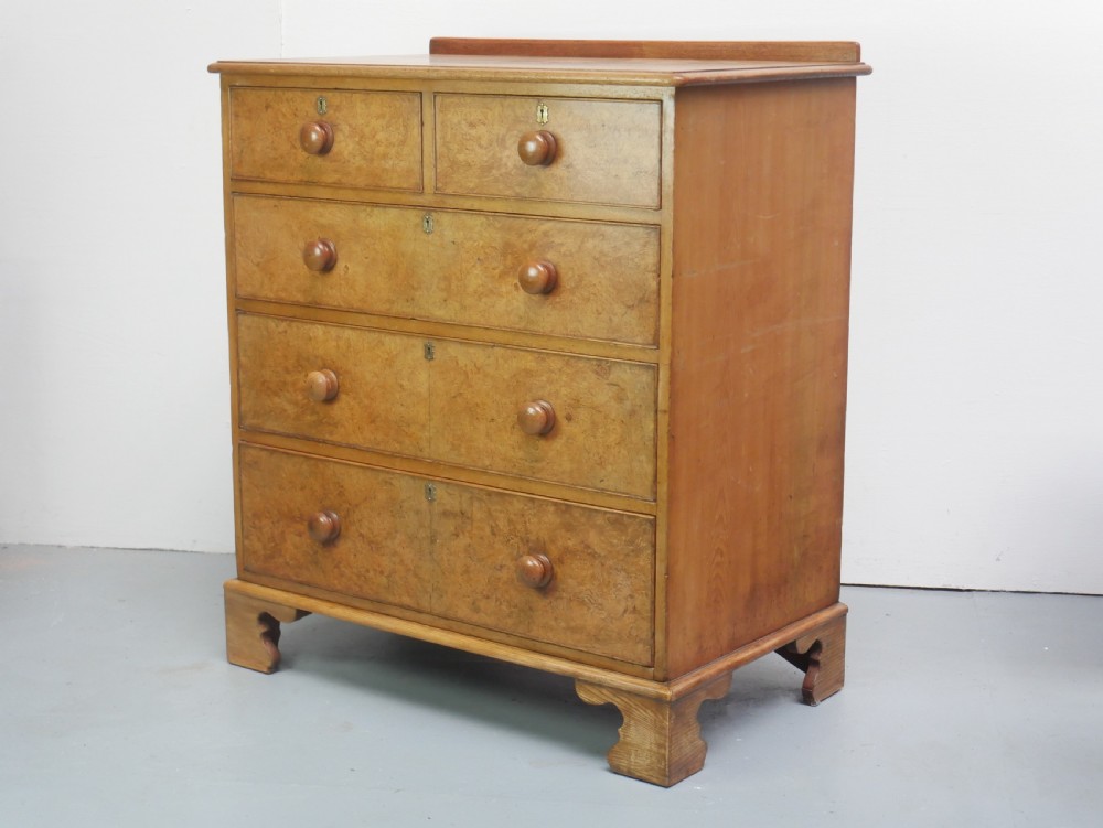 An antique burr ash chest of drawers featuring two short over three long graduated drawers with turned wooden knobs and bracket feet. View IX