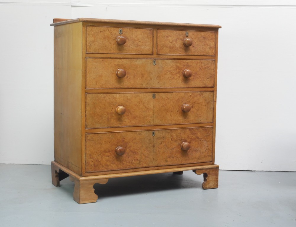 An antique burr ash chest of drawers featuring two short over three long graduated drawers with turned wooden knobs and bracket feet. View X