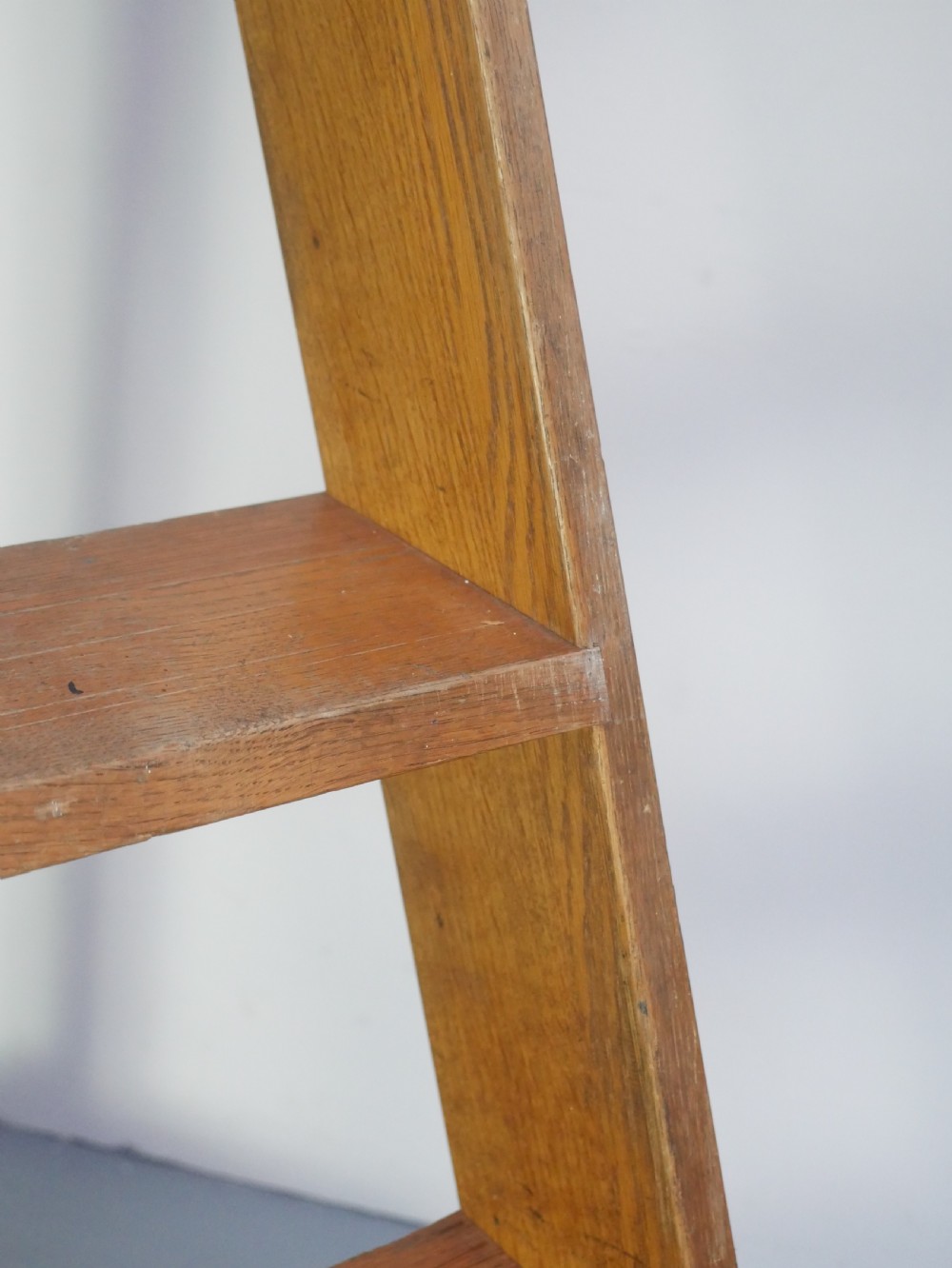 A tall freestanding oak library step ladder featuring multiple wide treads, shaped handholds at the top, and a warm natural wood finish. View III