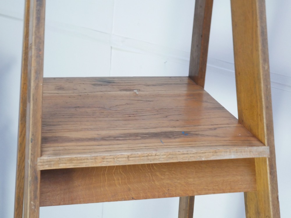 A tall freestanding oak library step ladder featuring multiple wide treads, shaped handholds at the top, and a warm natural wood finish. View IV
