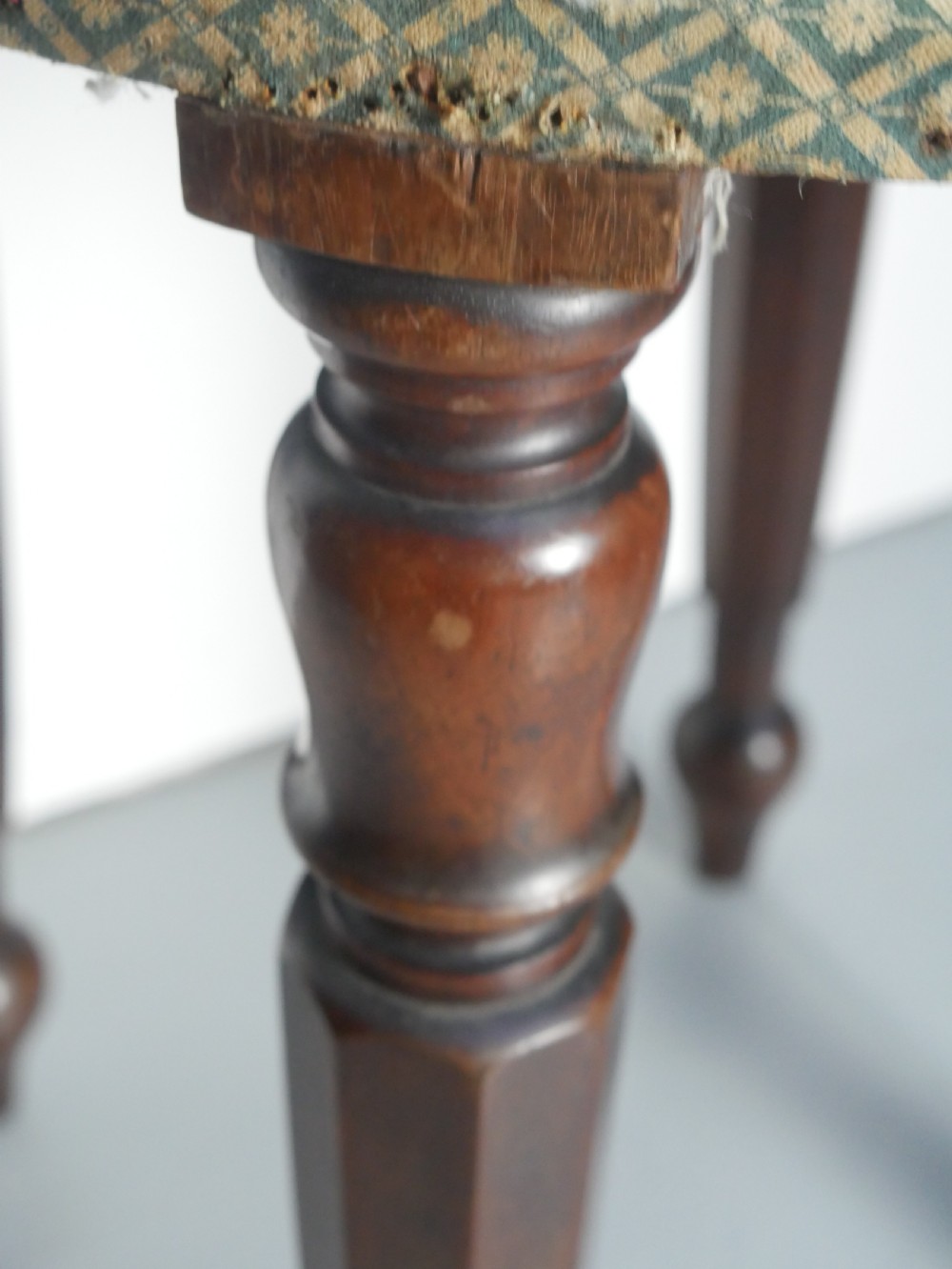 A circular stool with four dark turned timber legs and a padded circular top showing visible upholstery layers. View III