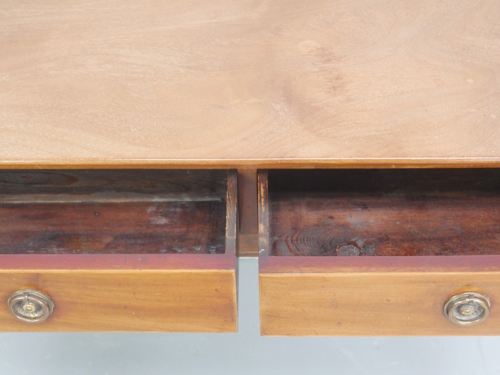 An antique mahogany writing table featuring a low gallery shelf, two drawers with circular brass pull handles, line inlay details, and four square tapered legs. View V