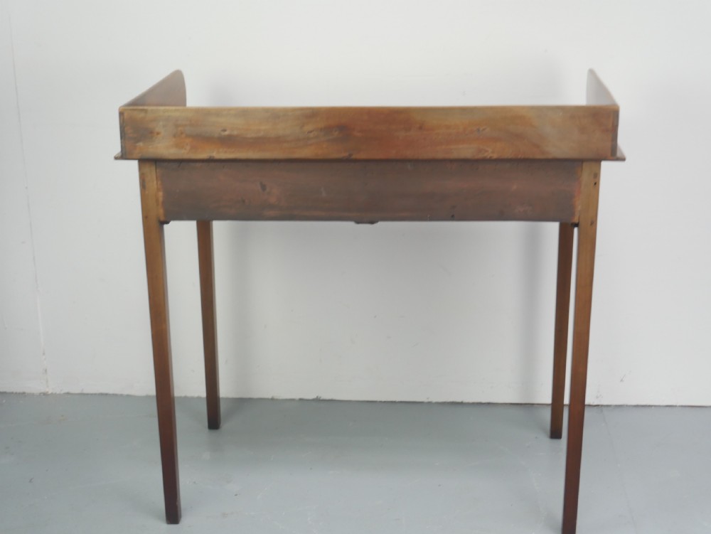 An antique mahogany writing table featuring a low gallery shelf, two drawers with circular brass pull handles, line inlay details, and four square tapered legs. View VIII