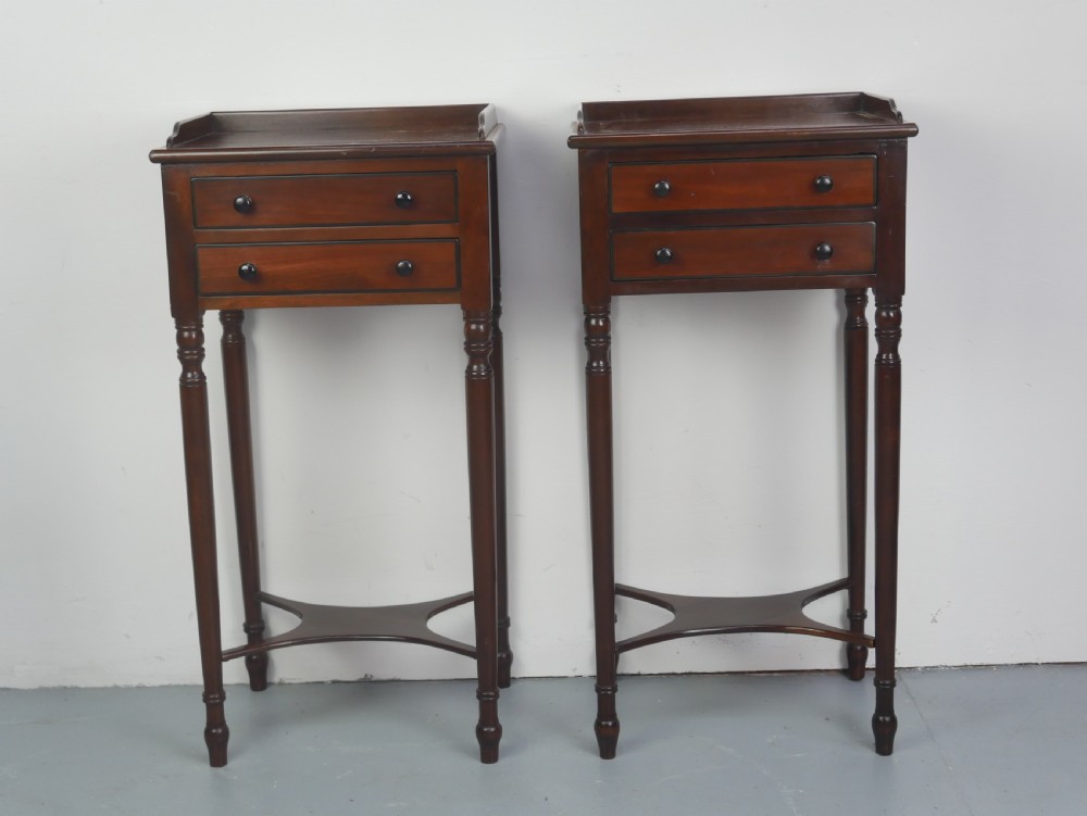 A pair of tall slim dark mahogany bedside tables featuring tray tops, two drawers with black knobs, turned legs, and curved X-frame stretchers. View VI