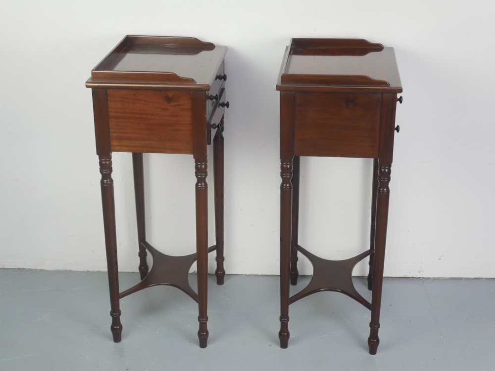 A pair of tall slim dark mahogany bedside tables featuring tray tops, two drawers with black knobs, turned legs, and curved X-frame stretchers. View VIII