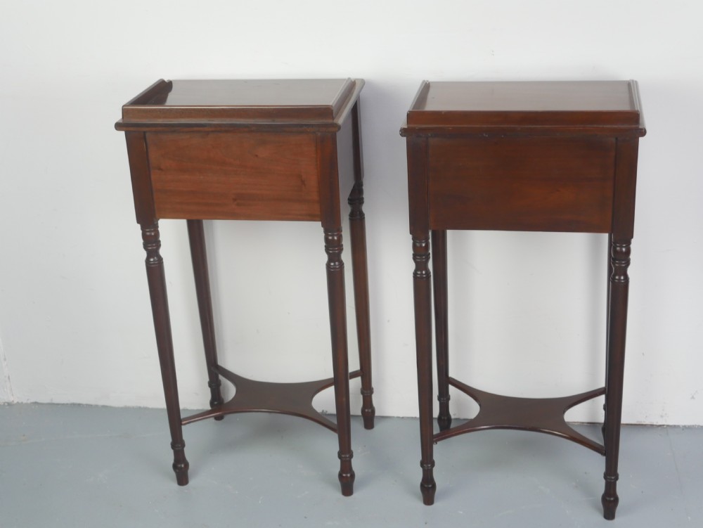 A pair of tall slim dark mahogany bedside tables featuring tray tops, two drawers with black knobs, turned legs, and curved X-frame stretchers. View IX