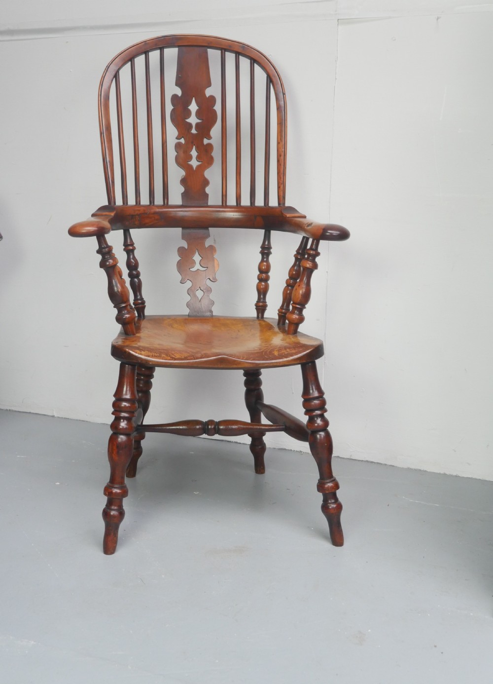 A 19th-century yewwood Windsor armchair featuring a high hoop back, central pierced fretwork splat, turned spindles, and a shaped wooden seat.