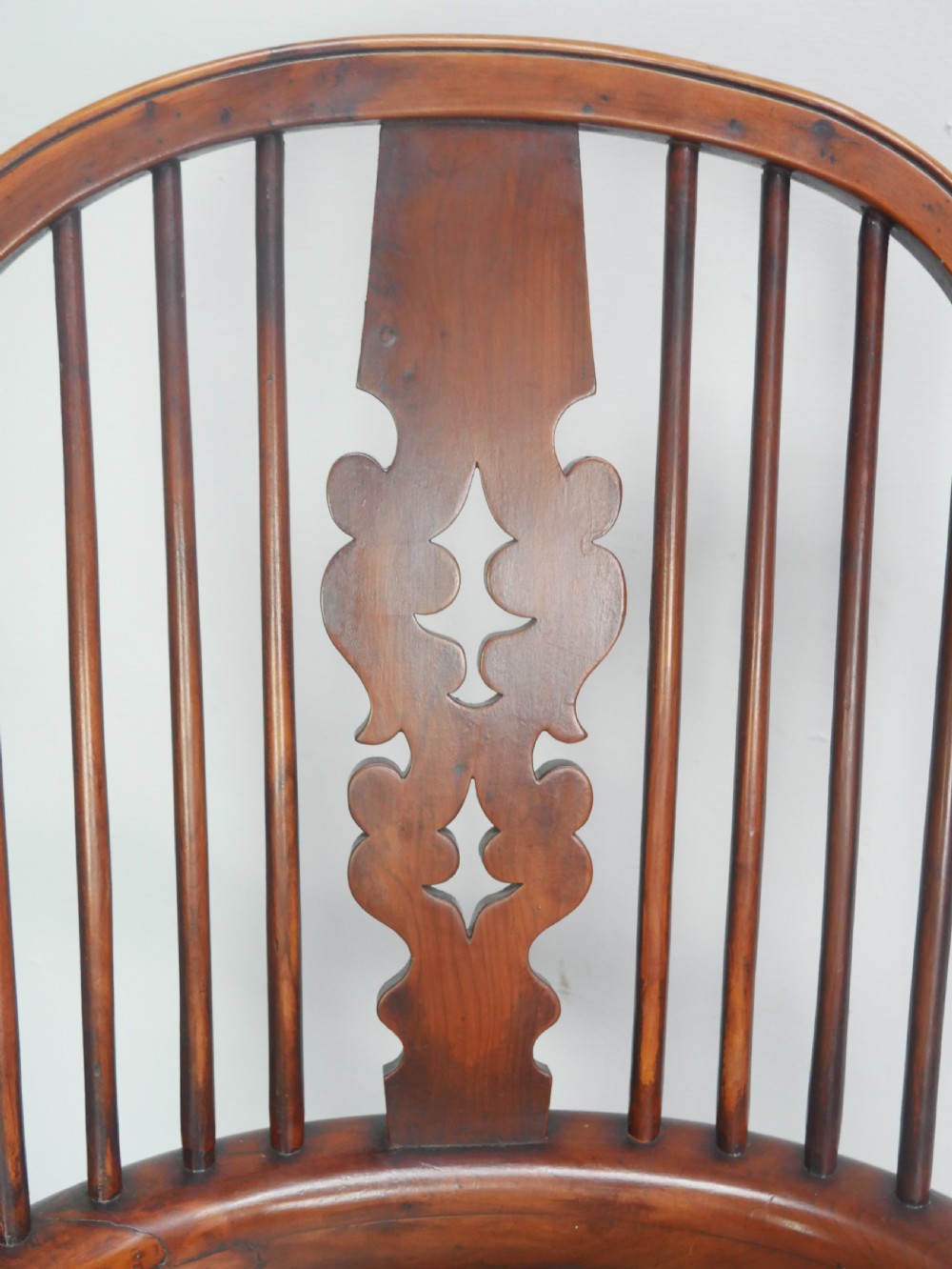 A 19th-century yewwood Windsor armchair featuring a high hoop back, central pierced fretwork splat, turned spindles, and a shaped wooden seat. View III