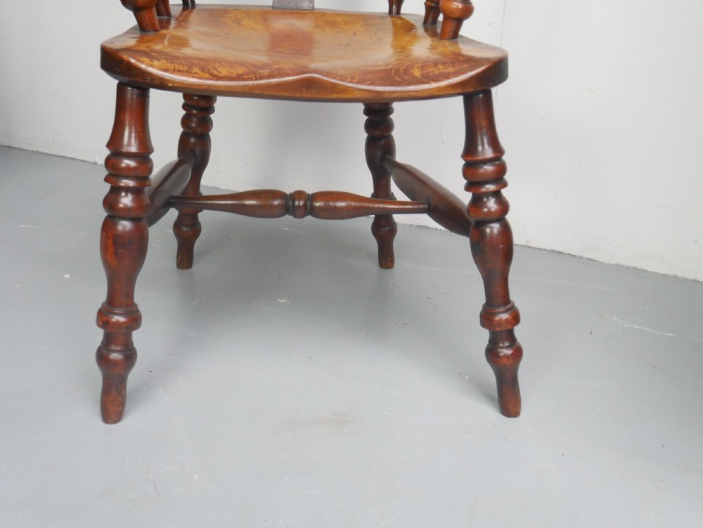 A 19th-century yewwood Windsor armchair featuring a high hoop back, central pierced fretwork splat, turned spindles, and a shaped wooden seat. View IV