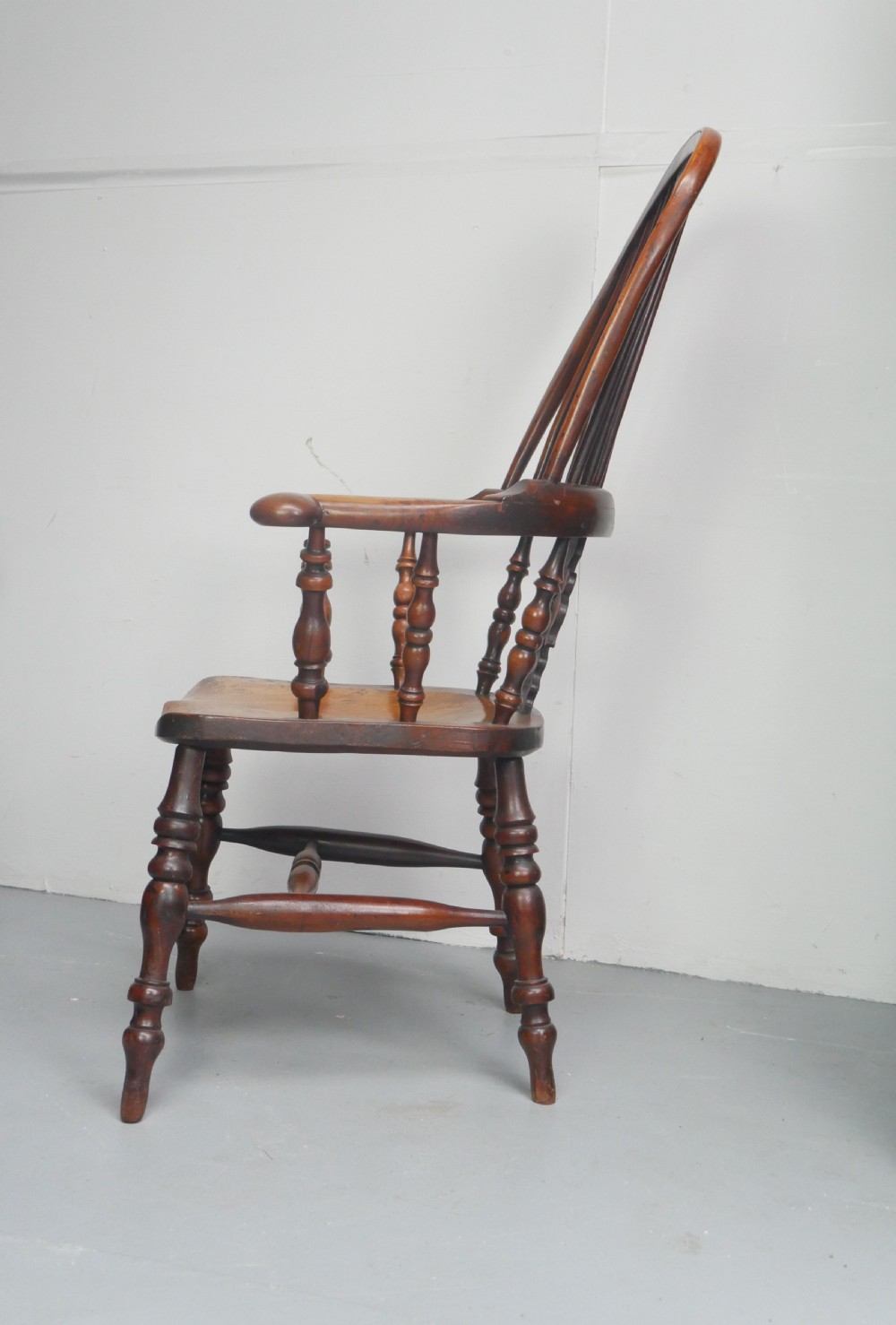 A 19th-century yewwood Windsor armchair featuring a high hoop back, central pierced fretwork splat, turned spindles, and a shaped wooden seat. View V