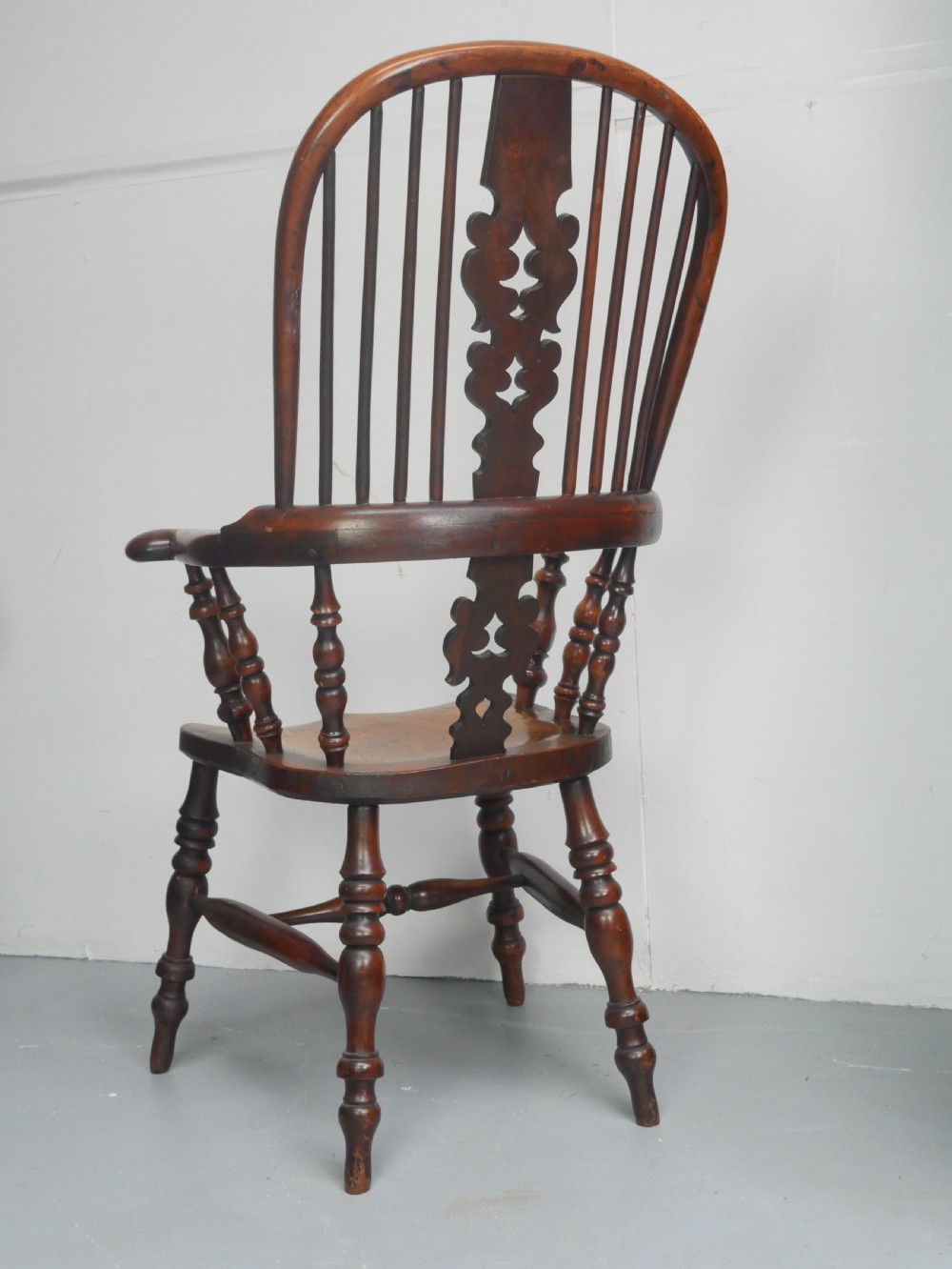 A 19th-century yewwood Windsor armchair featuring a high hoop back, central pierced fretwork splat, turned spindles, and a shaped wooden seat. View VI