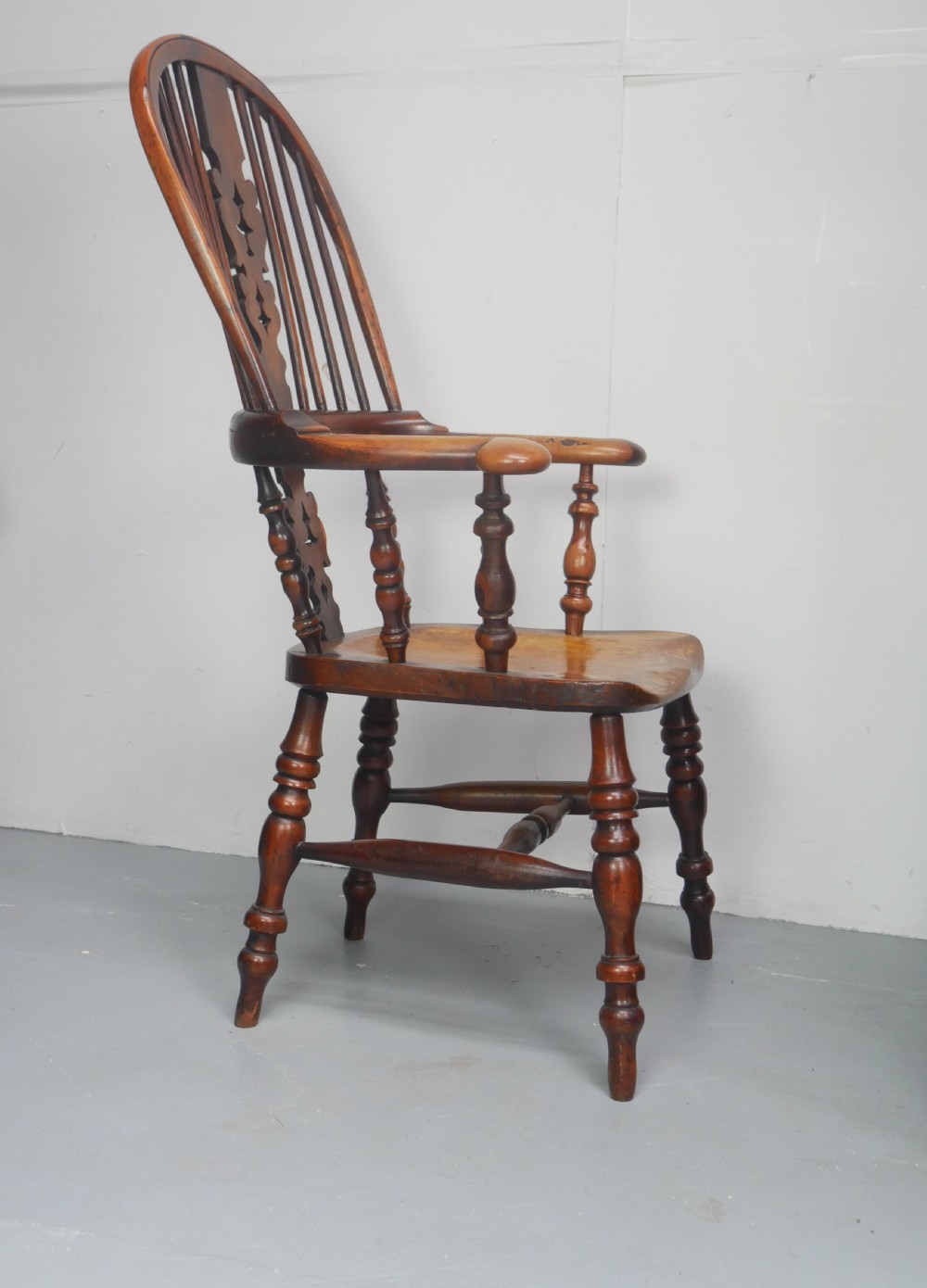 A 19th-century yewwood Windsor armchair featuring a high hoop back, central pierced fretwork splat, turned spindles, and a shaped wooden seat. View VIII