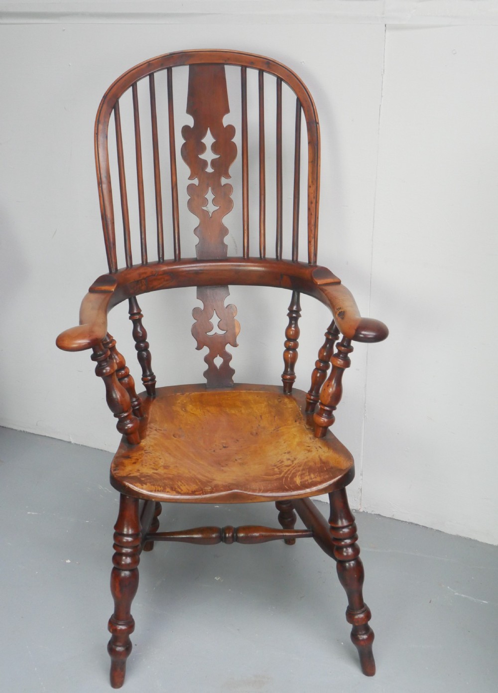 A 19th-century yewwood Windsor armchair featuring a high hoop back, central pierced fretwork splat, turned spindles, and a shaped wooden seat. View XIV