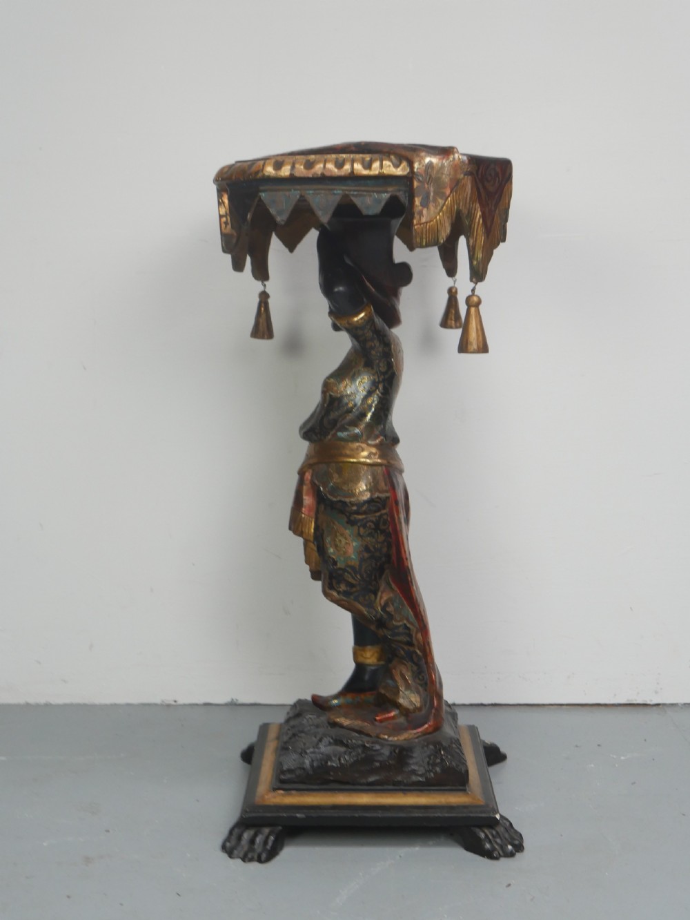 A 19th-century carved polychrome and gilded wooden Venetian side table depicting a figural stand supporting a draped canopy top with hanging tassels. View VI