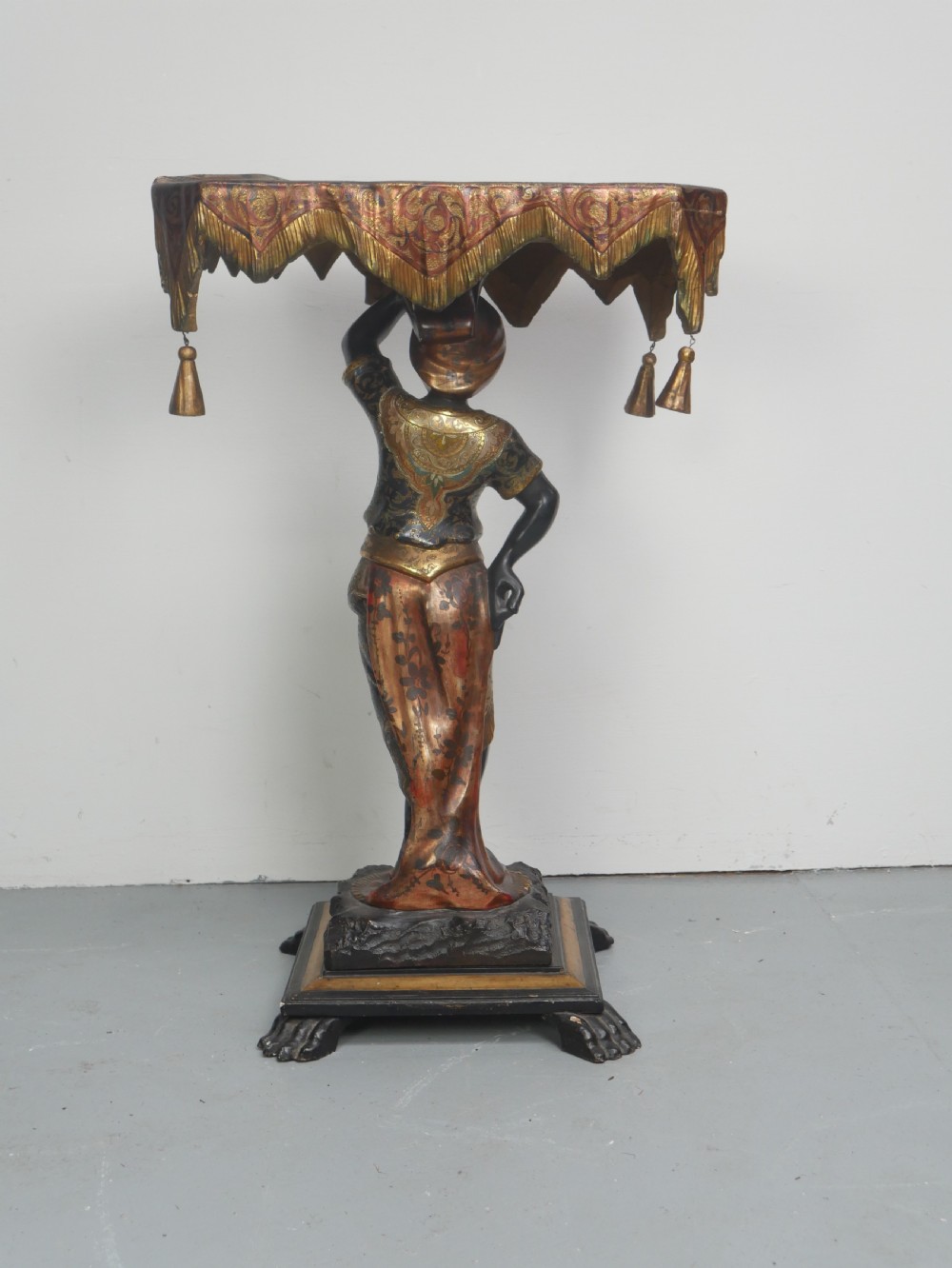 A 19th-century carved polychrome and gilded wooden Venetian side table depicting a figural stand supporting a draped canopy top with hanging tassels. View VIII
