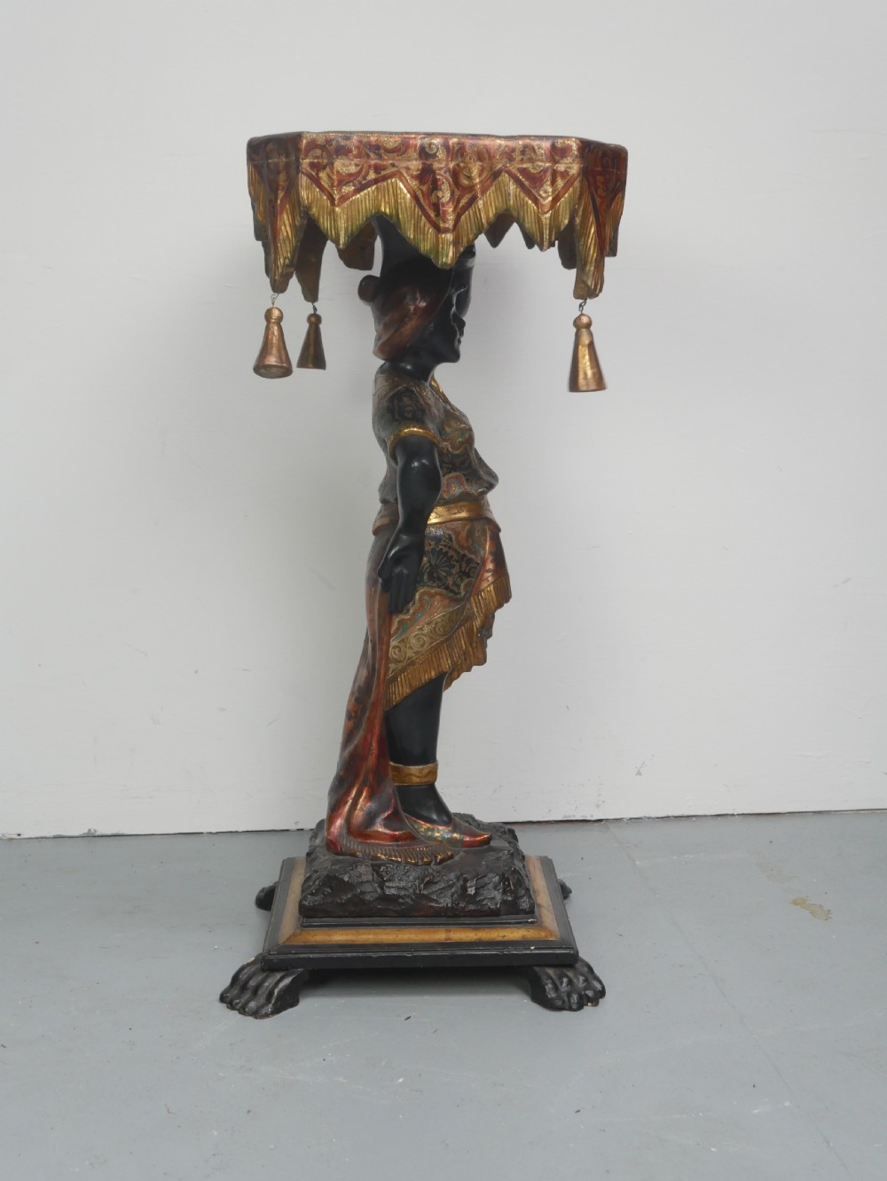A 19th-century carved polychrome and gilded wooden Venetian side table depicting a figural stand supporting a draped canopy top with hanging tassels. View X