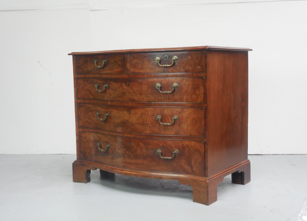 An eighteenth-century Georgian serpentine-fronted mahogany chest of drawers featuring brass swan-neck handles and bracket feet.
