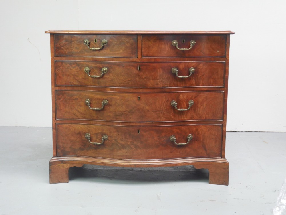 An eighteenth-century Georgian serpentine-fronted mahogany chest of drawers featuring brass swan-neck handles and bracket feet. View II