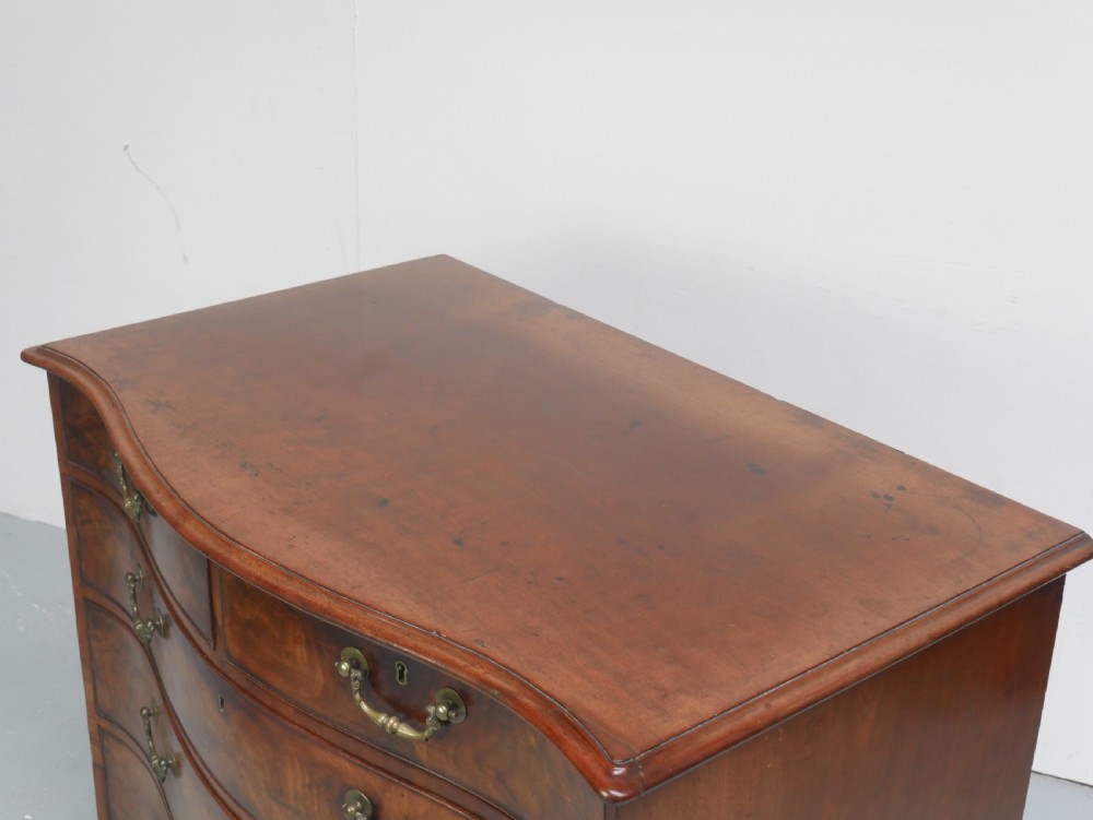 An eighteenth-century Georgian serpentine-fronted mahogany chest of drawers featuring brass swan-neck handles and bracket feet. View III