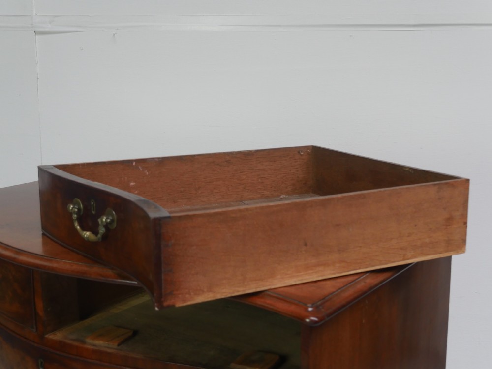 An eighteenth-century Georgian serpentine-fronted mahogany chest of drawers featuring brass swan-neck handles and bracket feet. View VI