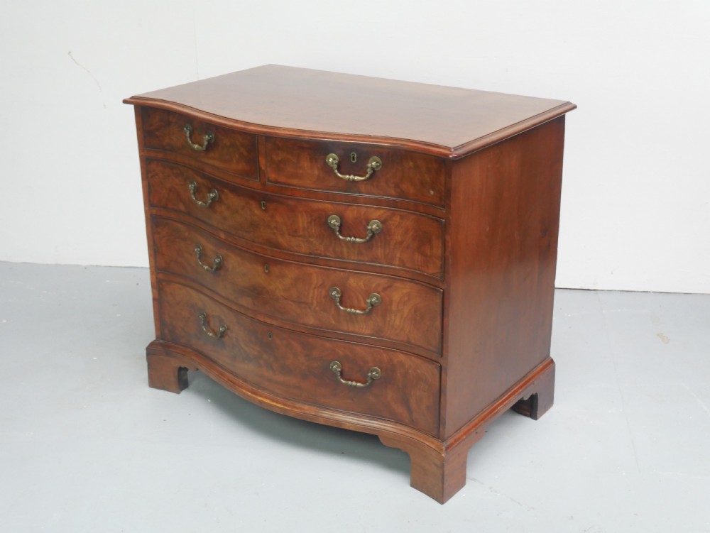 An eighteenth-century Georgian serpentine-fronted mahogany chest of drawers featuring brass swan-neck handles and bracket feet. View IX