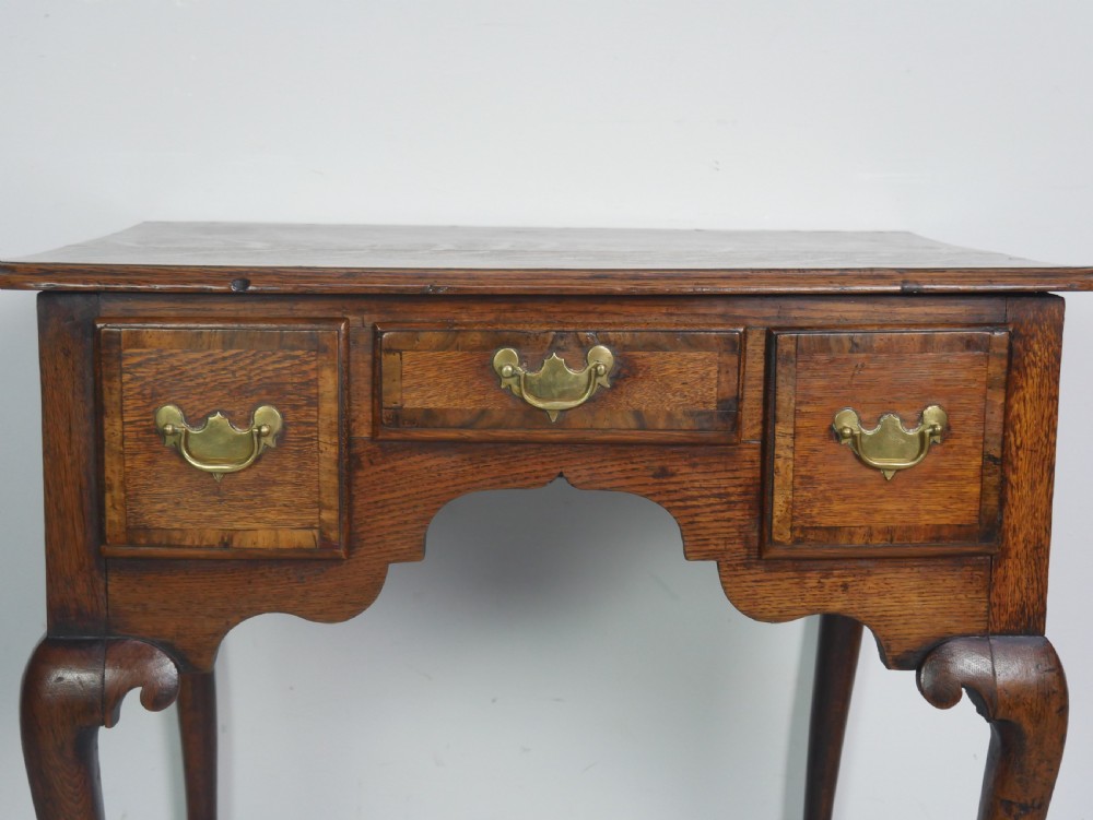 An eighteenth-century Georgian oak lowboy table featuring three drawers with brass handles, a shaped apron, and four cabriole legs ending in pad feet. View III