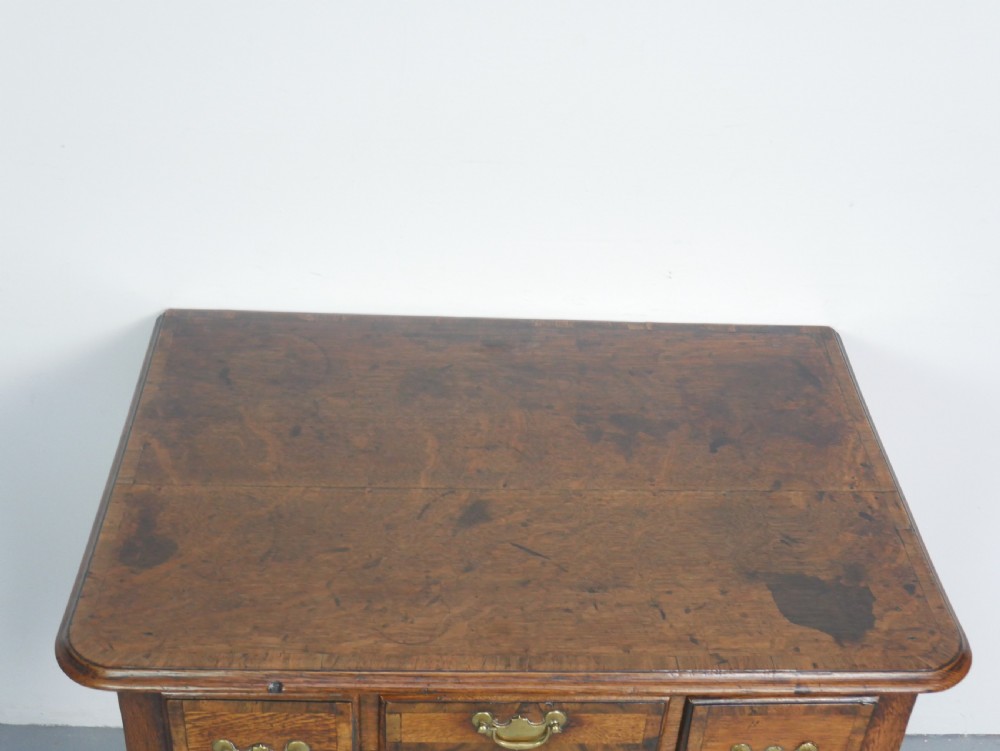 An eighteenth-century Georgian oak lowboy table featuring three drawers with brass handles, a shaped apron, and four cabriole legs ending in pad feet. View IV