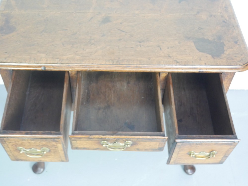An eighteenth-century Georgian oak lowboy table featuring three drawers with brass handles, a shaped apron, and four cabriole legs ending in pad feet. View V