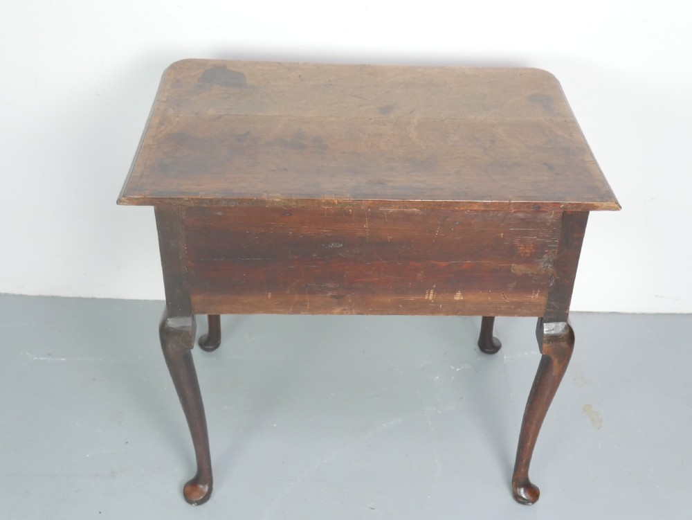 An eighteenth-century Georgian oak lowboy table featuring three drawers with brass handles, a shaped apron, and four cabriole legs ending in pad feet. View X
