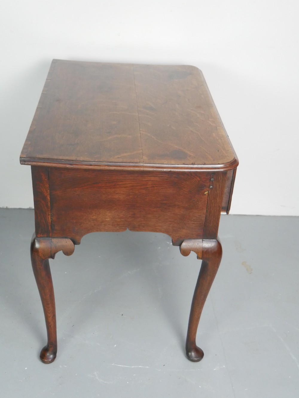 An eighteenth-century Georgian oak lowboy table featuring three drawers with brass handles, a shaped apron, and four cabriole legs ending in pad feet. View XI