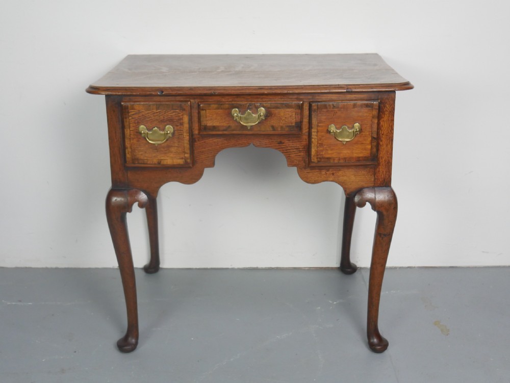An eighteenth-century Georgian oak lowboy table featuring three drawers with brass handles, a shaped apron, and four cabriole legs ending in pad feet. View XIV